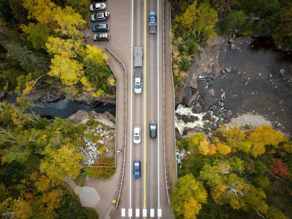 Stunning aerial view of a bridge over a forest river with vibrant autumn colors in Minnesota.